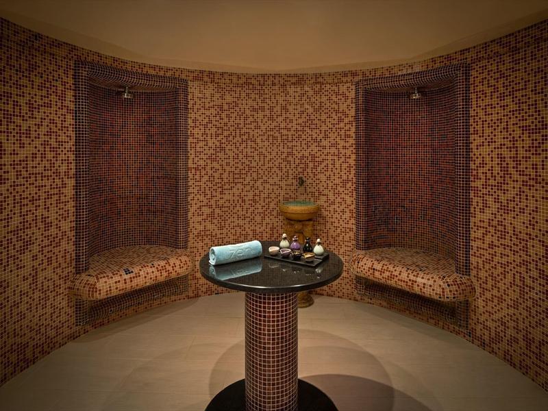 Runder Raum mit braunen, gemusterten Wänden, zwei Nischenbänken und einem kleinen runden Tisch.