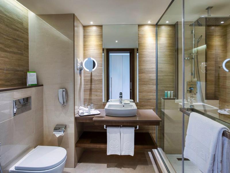 Modernes Badezimmer mit weißem WC, großem Spiegel, Glasdusche und Holzakzenten.