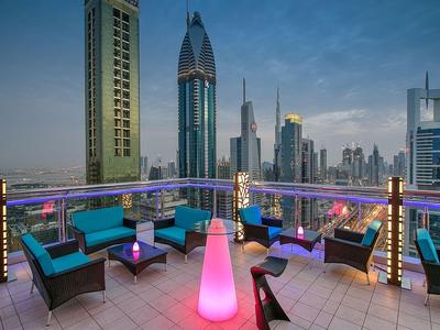 Dachterrasse mit moderner Beleuchtung und Sitzgelegenheiten mit Blick auf die Stadt bei Abenddämmerung