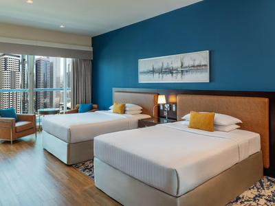 Modernes Hotelzimmer mit zwei Einzelbetten, großem Fenster und Sitzbereich.