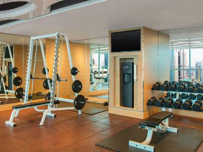 Moderner Fitnessraum mit Hantelbänken, Spiegeln und Gewichten in Hotelumgebung.