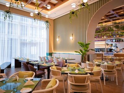 Elegantes Hotelrestaurant mit bequemen Stühlen, großen Fenstern und moderner Einrichtung.