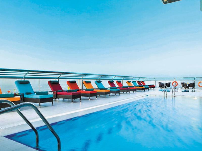 Hotelpool mit bunten Sonnenliegen und klar blauem Wasser unter klarem Himmel