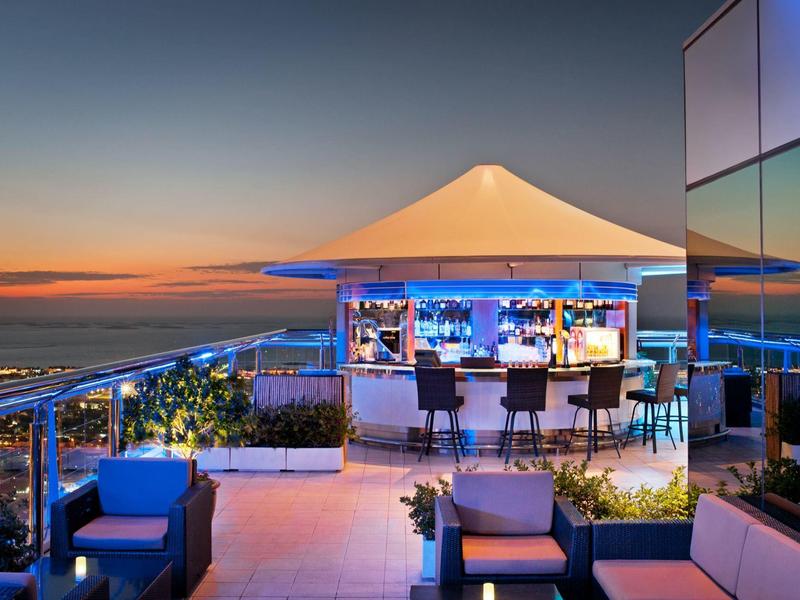 Elegante Dachbar mit Sitzgelegenheiten und Blick auf den Sonnenuntergang und das Meer.