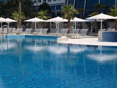 Großer Swimmingpool mit Sonnenschirmen und Liegestühlen in tropischer Hotelanlage
