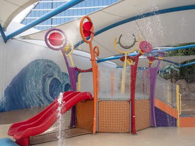 Bunter Indoor-Spielplatz mit roter Rutsche, Kletterelementen und Wellenwandgestaltung.