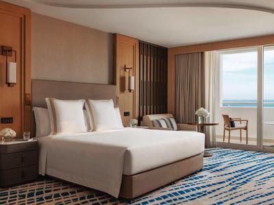 Modernes Hotelzimmer mit großem Bett, Balkon und Meerblick.