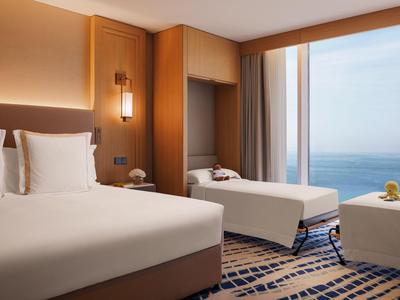 Modernes Hotelzimmer mit zwei Betten, Meerblick und warmem Holzdekor.