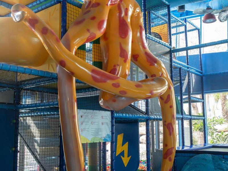 Großes orangefarbenes Oktopus-Spielgerät in einer bunten Indoor-Spielhalle.