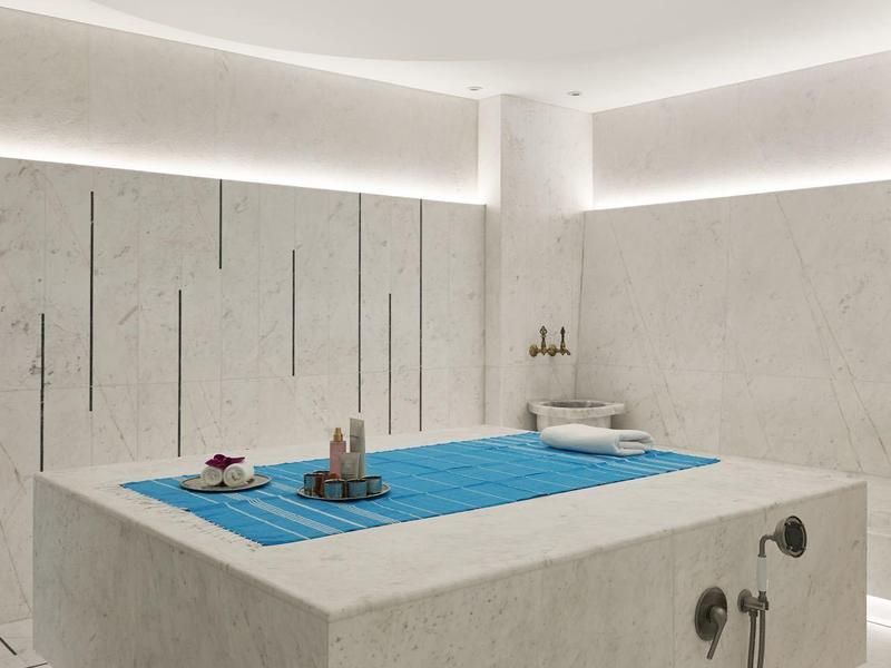 Moderner Wellnessraum mit quadratischem Betonpool, dezenter Beleuchtung und minimalistischer Einrichtung.