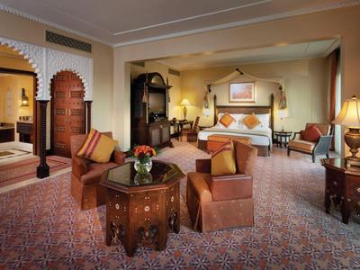 Luxuriös eingerichtete Hotellounge mit Sesseln, Teppichboden und dekorativem Himmelbett.