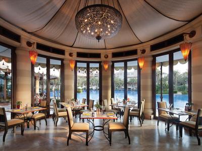 Elegantes Rundrestaurant mit Kronleuchter, großen Fenstern und Blick auf den Pool.