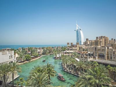 Stadt mit Wasserkanal, Palmen und modernen Gebäuden unter klarem blauem Himmel.