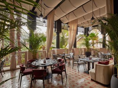 Elegantes Restaurant mit Pflanzen, braunen Stühlen und großer Fensterfront in hellem Raum.