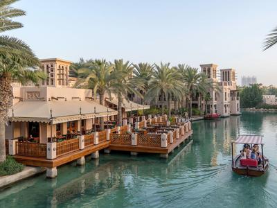 Traditionelle arabische Gebäude am Wasser mit Holzterrassen und einem kleinen Boot auf dem Kanal.