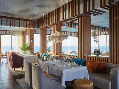 Restaurant élégant avec vue sur la mer, boiseries et tables dressées en blanc