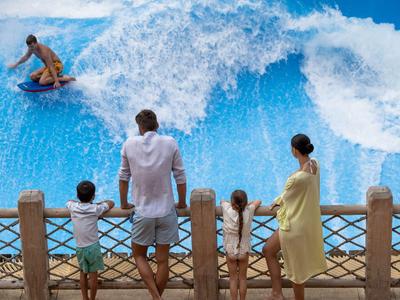 Familie beobachtet Surfer auf künstlicher Welle in Wasserpark