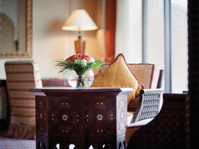 Bequeme Sitzgelegenheiten mit Kissen und dekorativem Tisch mit Blumen in elegantem Hotelzimmer.