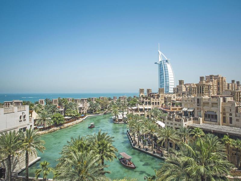Stadt mit Wasserkanal, Palmen und modernen Gebäuden unter klarem blauem Himmel.