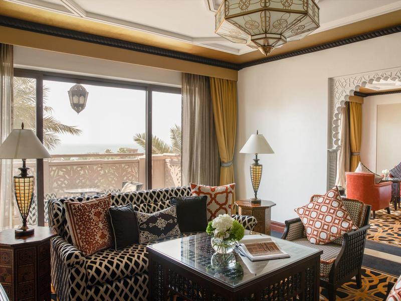 Elegantes Wohnzimmer mit gemusterten Sofas, zwei Lampen, einem Tisch und dekorativen Kissen.