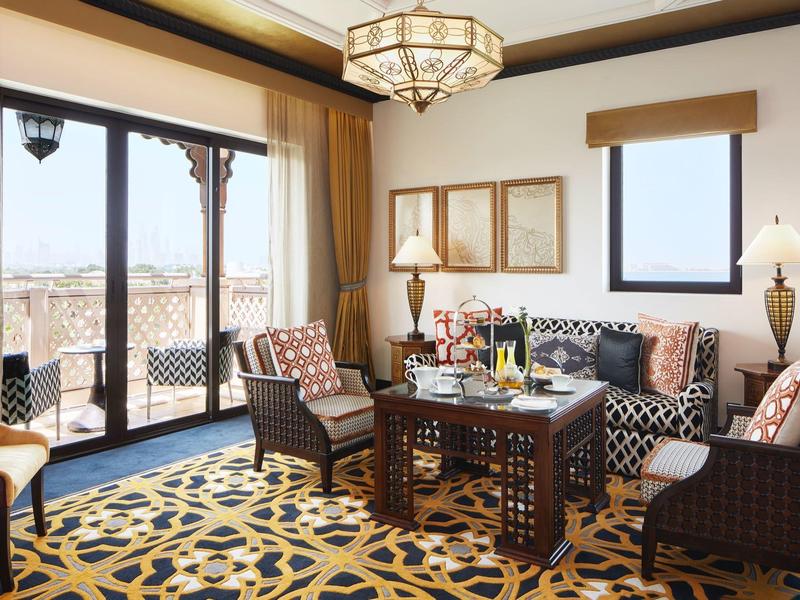 Helles Wohnzimmer mit großem Fenster, gemustertem Teppich und dunkelbraunen Möbeln aus Holz.