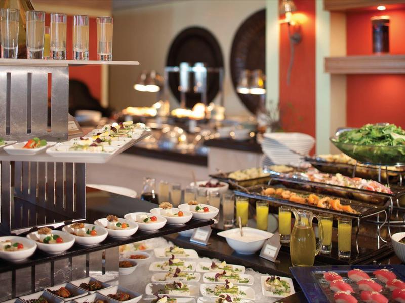 Buffet mit verschiedenen Speisen wie Salaten, Sushi und Getränken in elegantem Ambiente.