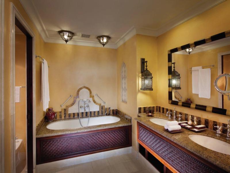 Gemütliches Badezimmer mit großer Badewanne, Spiegel, sanfter Beleuchtung und warmen Farben.