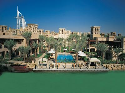 Luxushotel mit Pool, Palmen und traditioneller Architektur vor dem Burj Al Arab in Dubai.