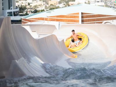 Person auf gelbem Schlauchboot auf einer Wasserrutsche im Wasserpark.
