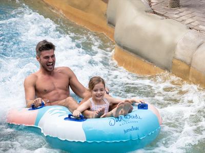 Mann und Kind fahren gemeinsam in einem Doppelreifen auf Wasser im Freizeitpark.