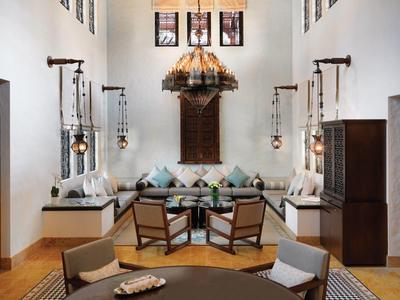 Helles Wohnzimmer mit Holzstühlen, Sofa, großen Fenstern und einem auffälligen Lampenschirm.