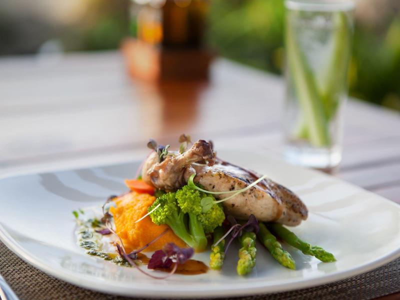 Ein Teller mit gebratenem Fleisch, Spargel und Kartoffelpüree, garniert mit Kräutern und Sauce.