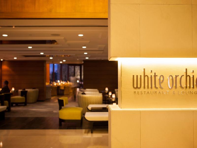 Eingang zum Restaurant White Orchid mit warmem Licht und moderner, gemütlicher Einrichtung.