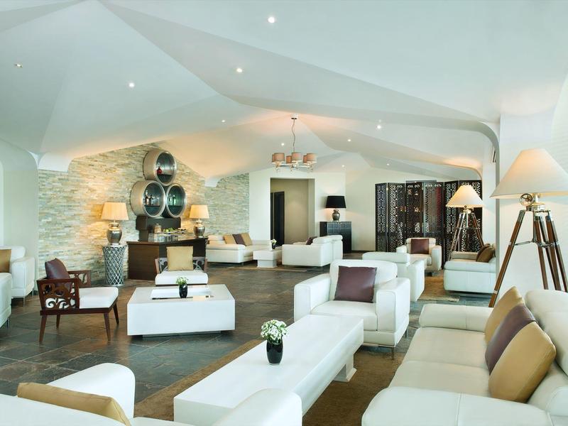 Großer, moderner Wohnraum mit weißen Sofas, dunklen Holzmöbeln und dekorativer Beleuchtung.