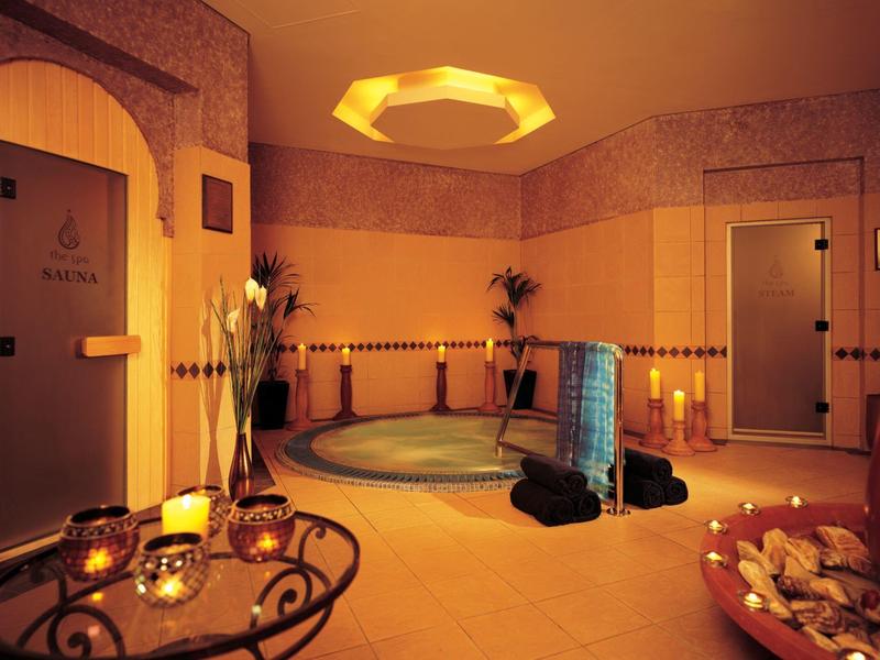 Gemütlicher Wellnessraum mit Whirlpool, weichen Handtüchern, Kerzenlicht und entspannt warmer Beleuchtung.