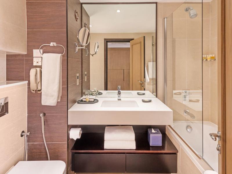 Baño de hotel moderno con lavabo doble, bañera y revestimiento de madera.