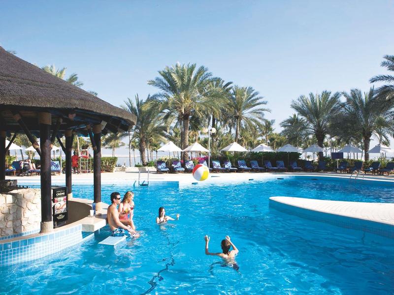 Niña baja alegremente por un tobogán amarillo en el área de juegos del hotel.