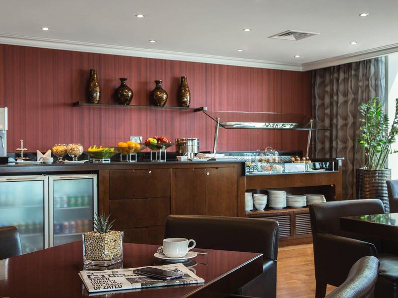 Moderne Frühstücksecke mit Holzmöbeln, gedecktem Tisch, Vitrinen und Buffet mit Geschirr und Speisen.