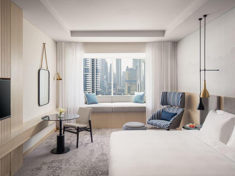 Modernes Hotelzimmer mit großem Fenster, bequemen Sitzmöglichkeiten und klaren, hellen Farben.