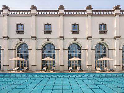 Elegante piscina al aire libre frente a un edificio blanco con arcos y ventanas