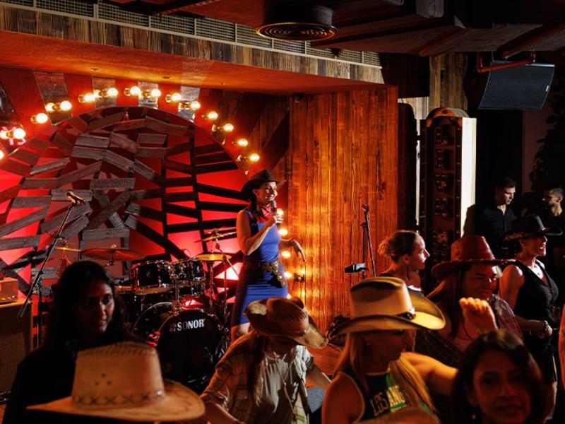 Personas disfrutan de una actuación musical en vivo en un entorno interior rústico con decoración de madera.