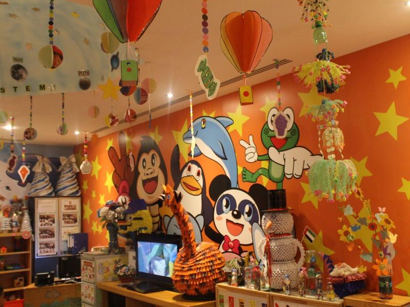 Zona infantil colorida con murales de personajes animados y decoración colgante en un hotel o restaurante.