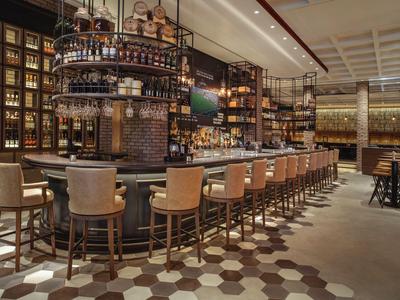 Modern eingerichtete Hotelbar mit Hockern und warmem, einladendem Licht.