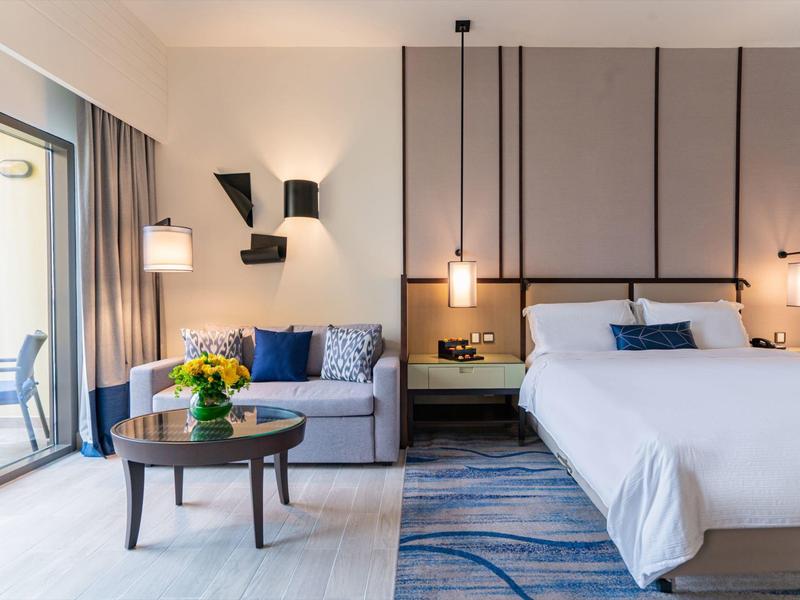 Habitación de hotel moderna con sofá cómodo, cama grande y decoración coordinada.