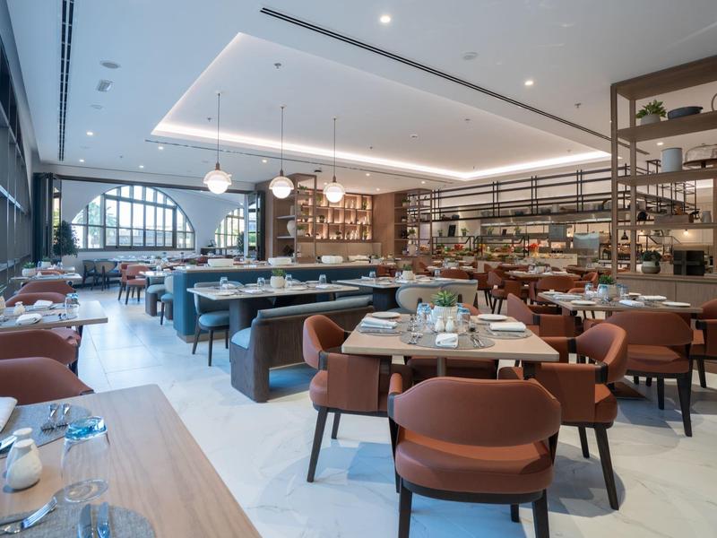 Restaurante moderno de hotel con sillas cómodas, grandes ventanas y ambiente acogedor.