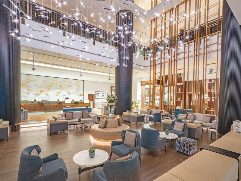 Salón moderno de hotel con sillas elegantes, mesas y iluminación sofisticada.