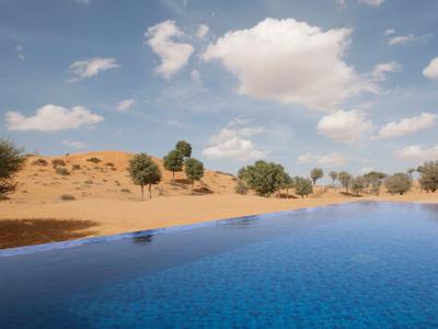 Luxuriöses Zelt mit großem Bett, Holzmöbeln, Teppichen und stimmungsvoller Beleuchtung.