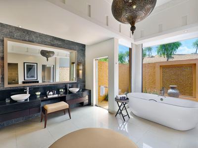 Helles Badezimmer mit freistehender Badewanne, großem Spiegel und Doppelwaschbecken in gedeckten Farben.