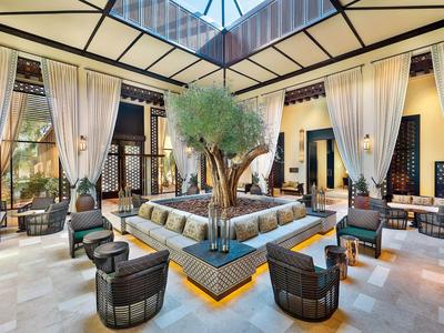 Großer, heller Innenraum mit zentralem Baum und stilvollen Sitzbereichen in einem Hotel.