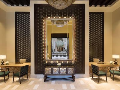 Eleganter Hotel-Empfangsbereich mit großen Spiegeln, Tischlampen und schwarzen Stühlen.